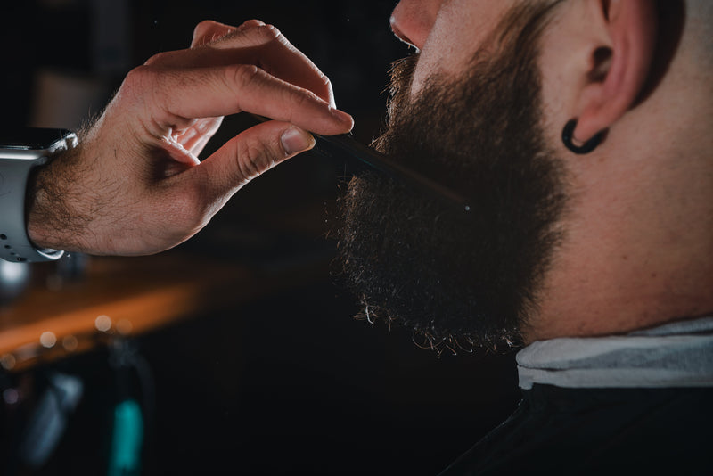 Man trimming and shaping his beard at home with grooming tools